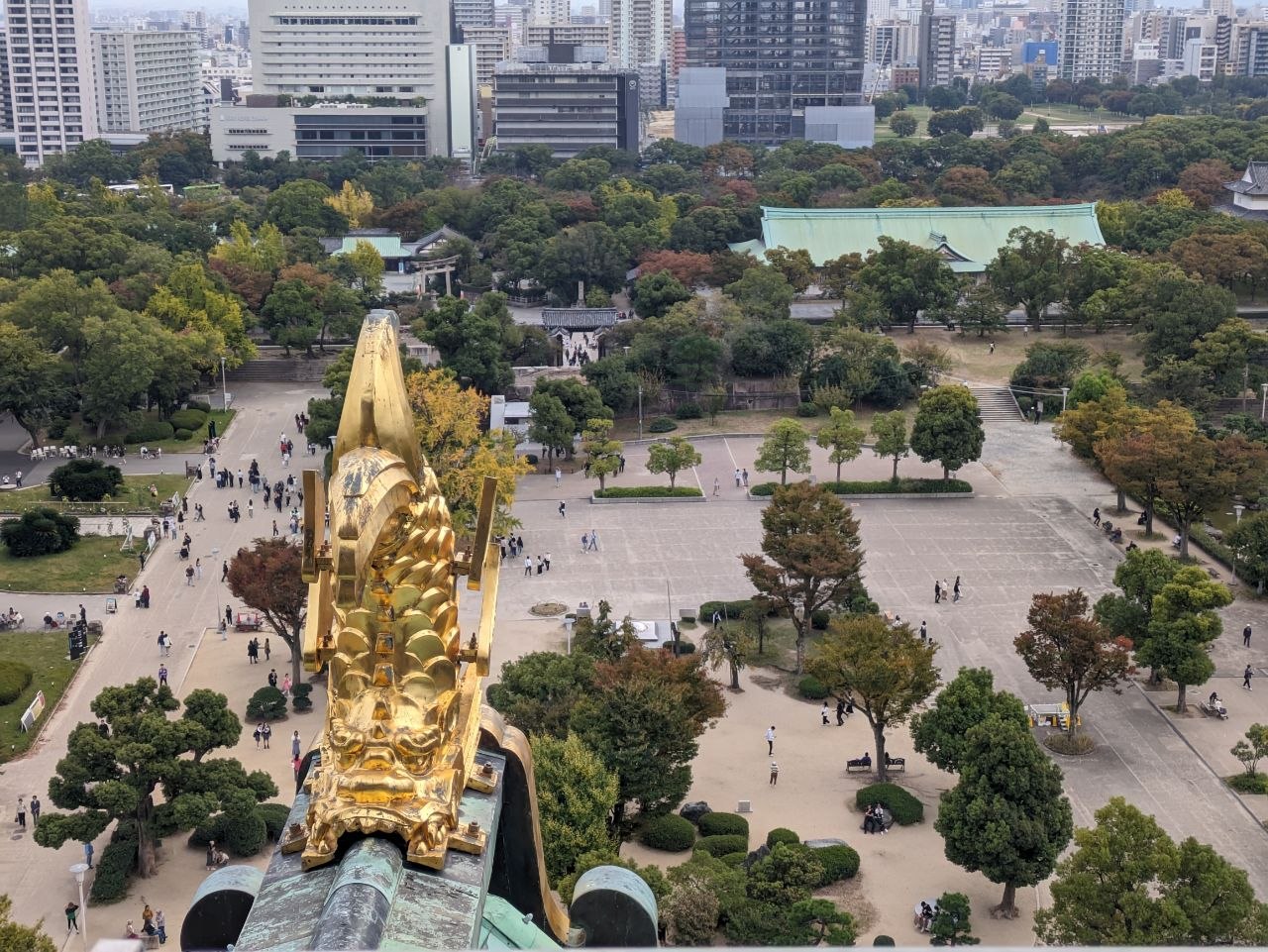 Golden shachihoko ornament atop Osaka Castle with park grounds below