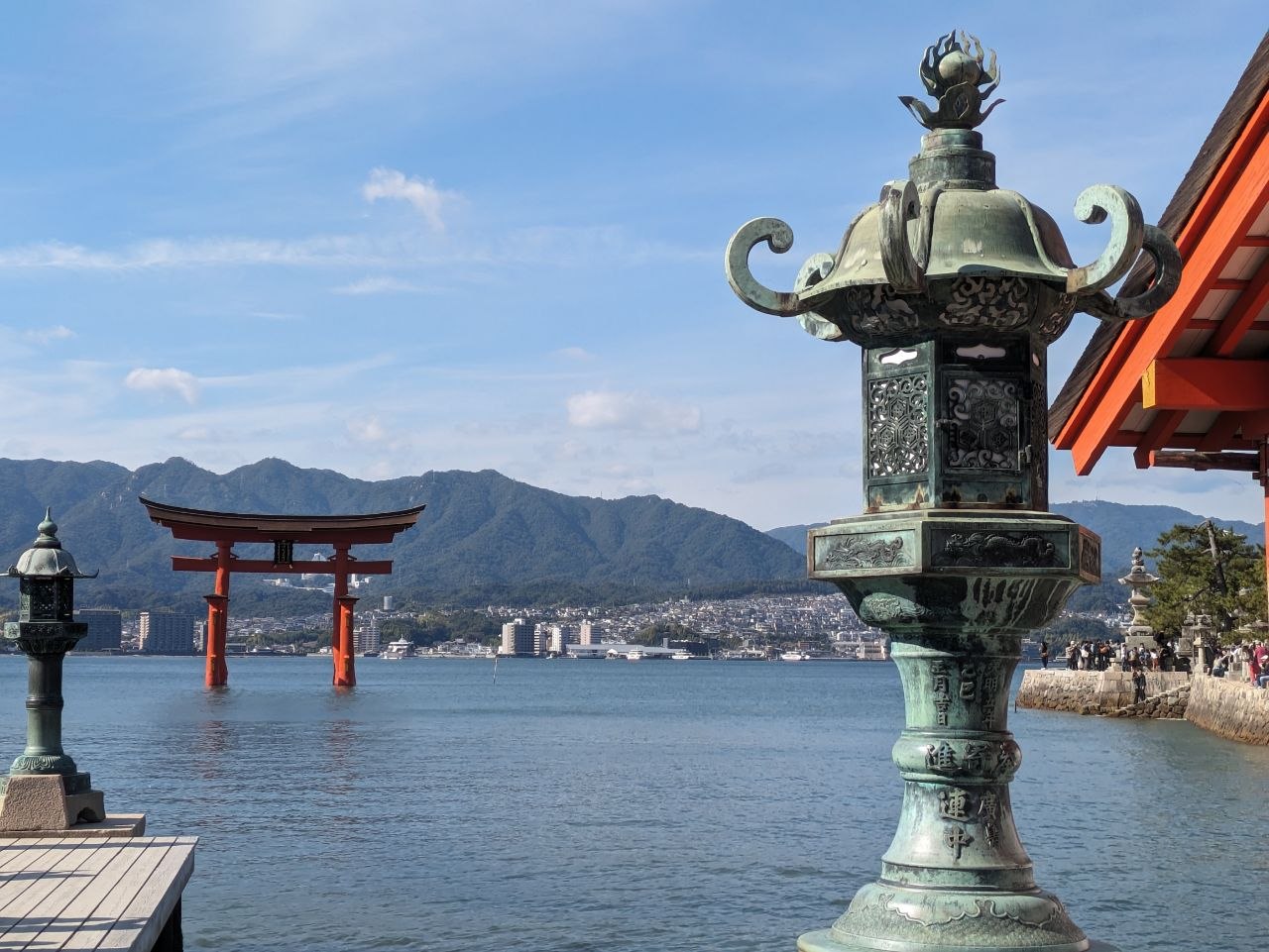 Bronze lantern with floating torii gate of Itsukushima in the background