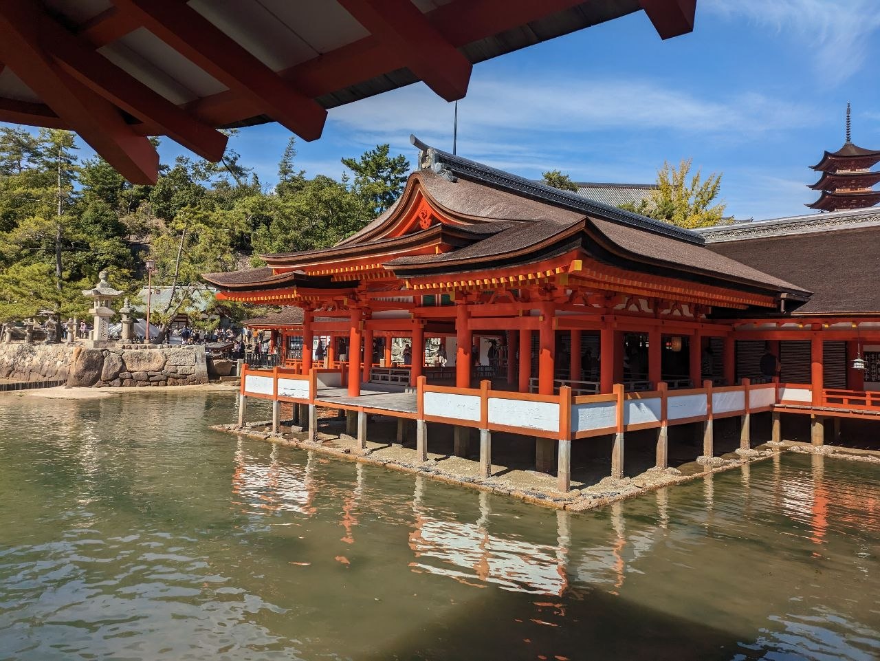 Itsukushima Shrine main hall built over tidal flats with five-storey pagoda in background