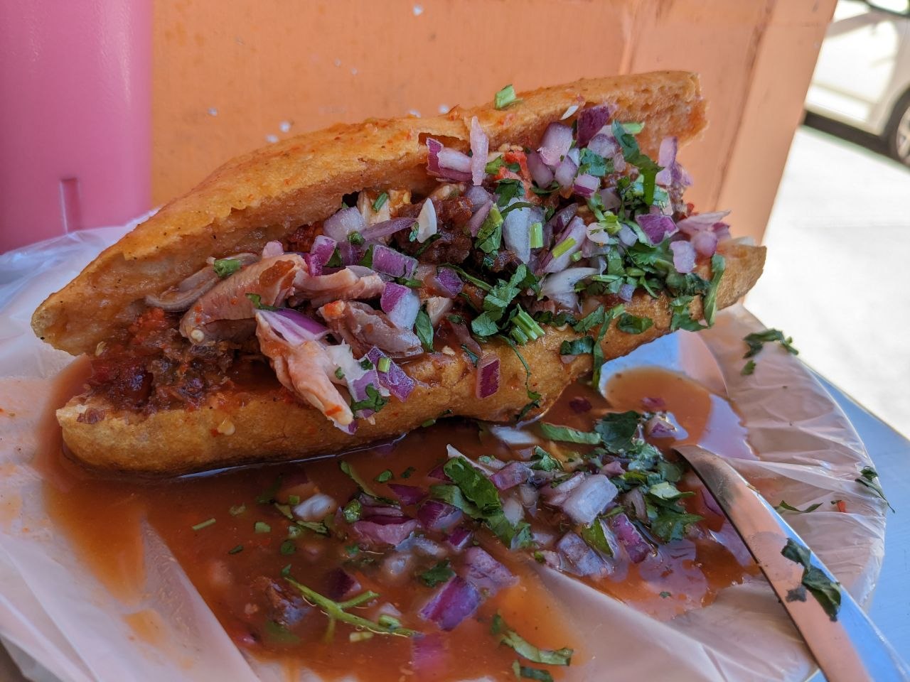 Torta ahogada drowned sandwich with pulled chicken, red salsa, onion and cilantro in Guadalajara
