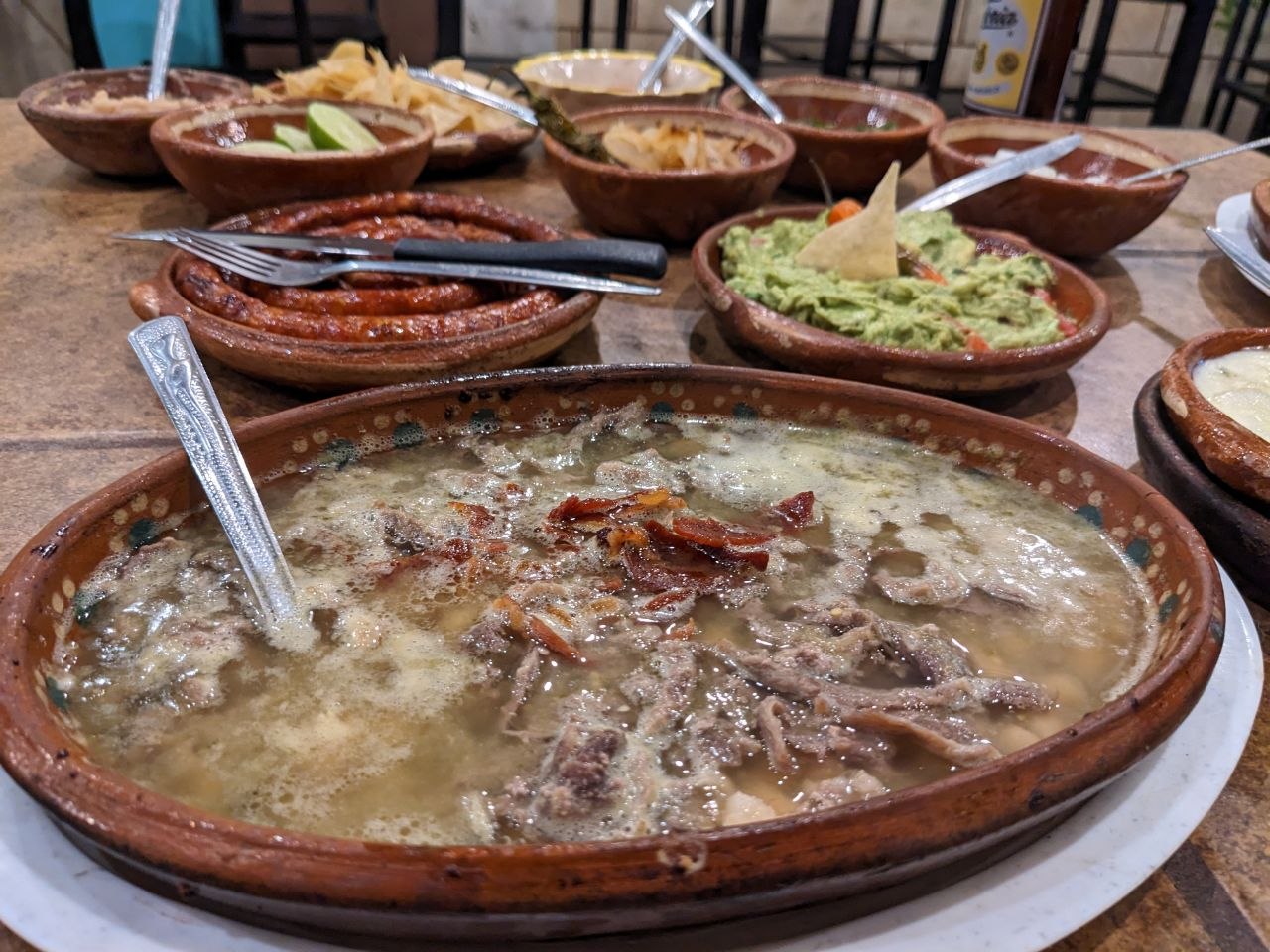 Birria served in a clay cazuela with guacamole and condiments in Guadalajara