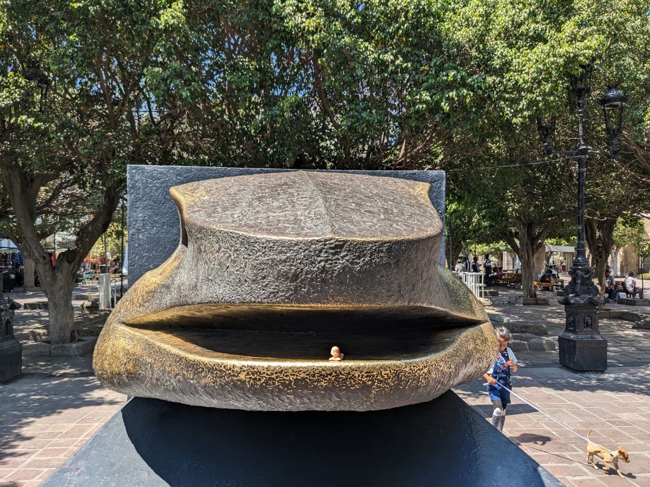 Large bronze lips sculpture with small figure inside on a pedestrian plaza in Guadalajara