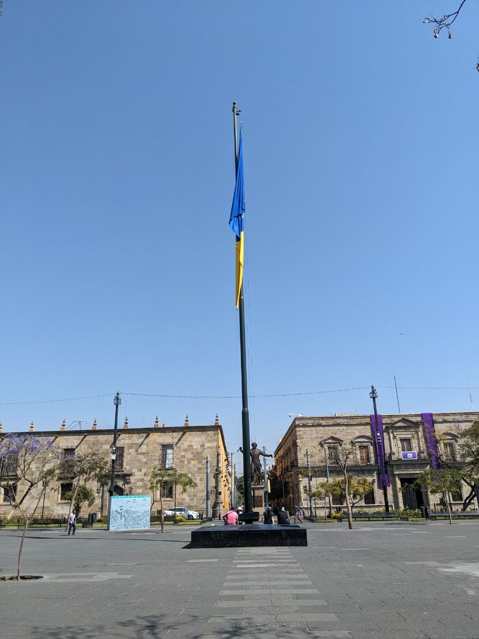 Jalisco flag flying on a tall flagpole in Plaza Guadalajara with colonial government buildings behind