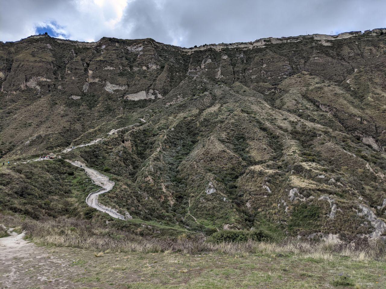 Steep zigzagging descent trail leading down the inner wall of the Quilotoa caldera toward the lake