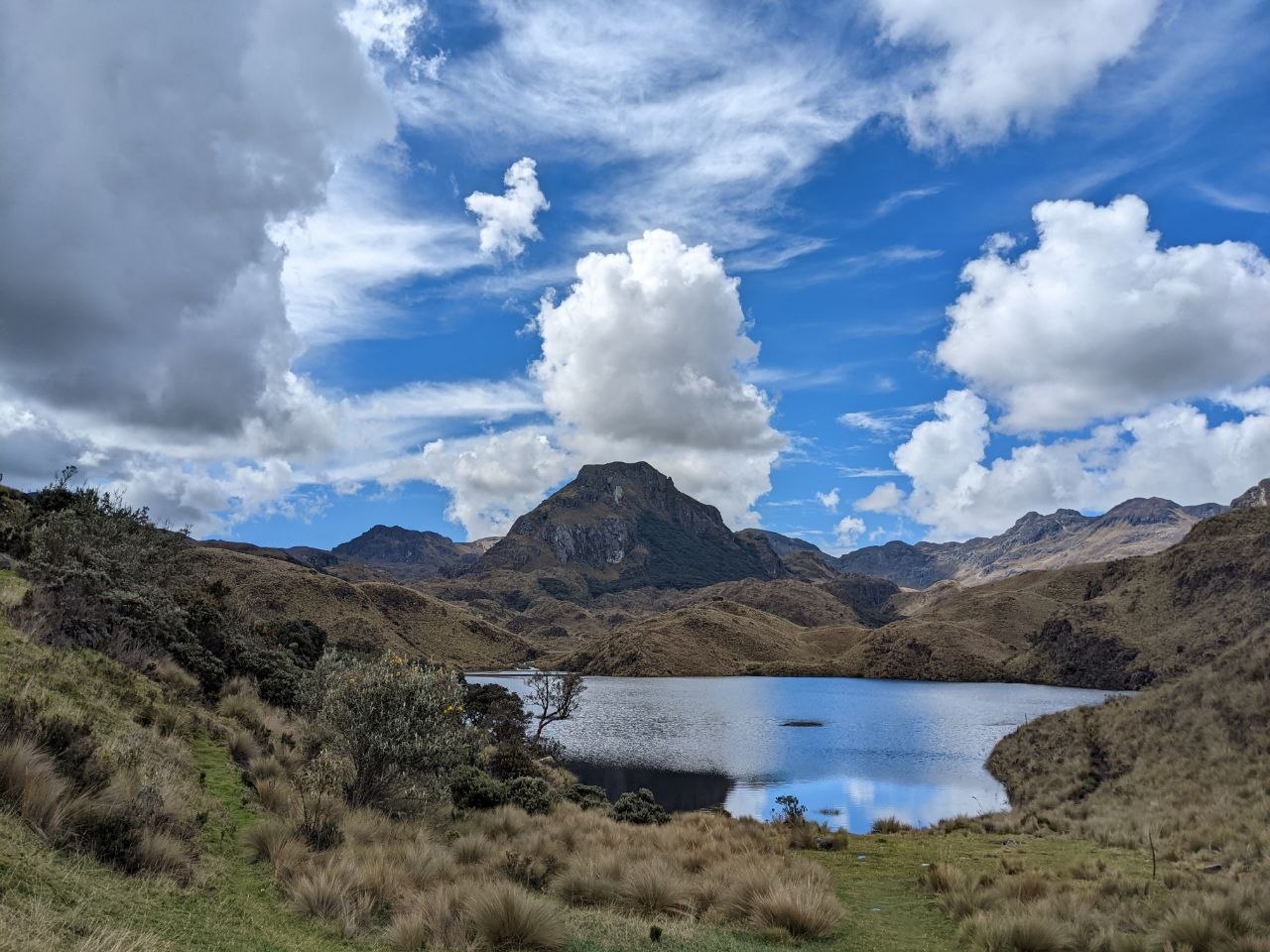 A glacial lake in Cajas National Park with páramo grasslands and a rocky Andean peak reflected in the calm water