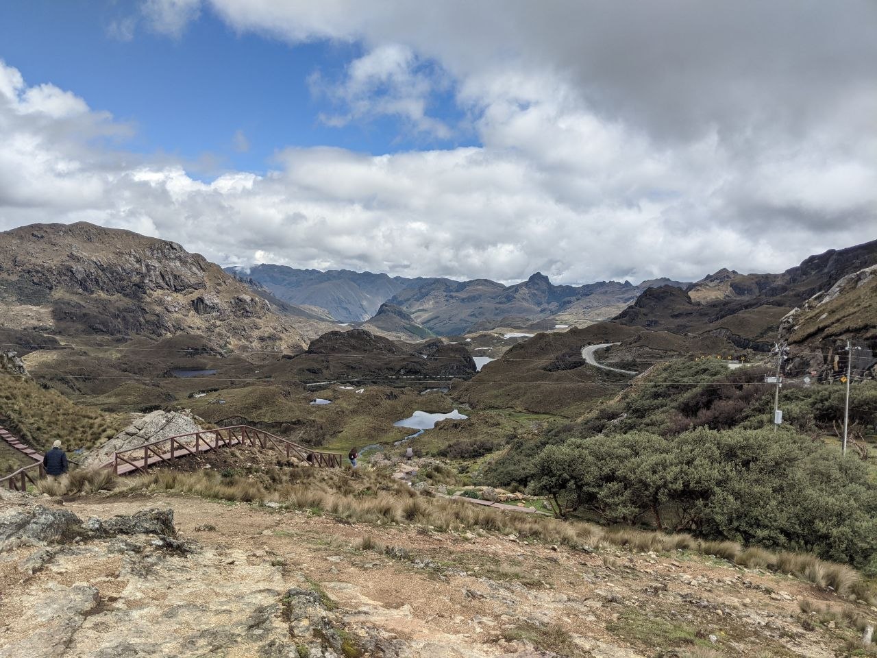 Panoramic view from Mirador Tres Cruces boardwalk over multiple lagoons and the interior of Cajas National Park with a winding road below