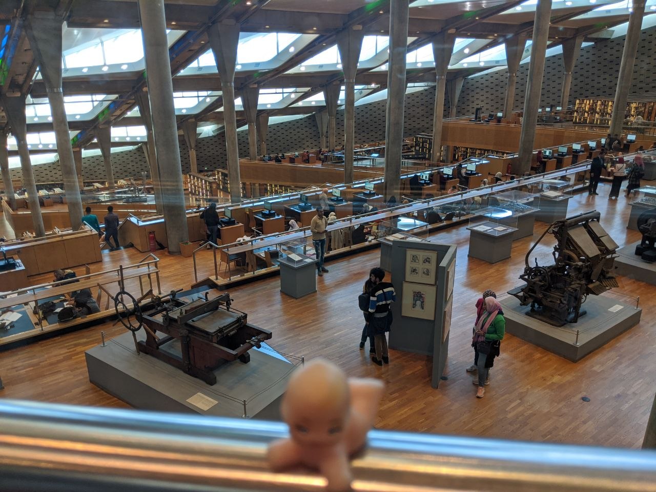 Interior of the Bibliotheca Alexandrina main reading room with cascading floors and historic printing press exhibits