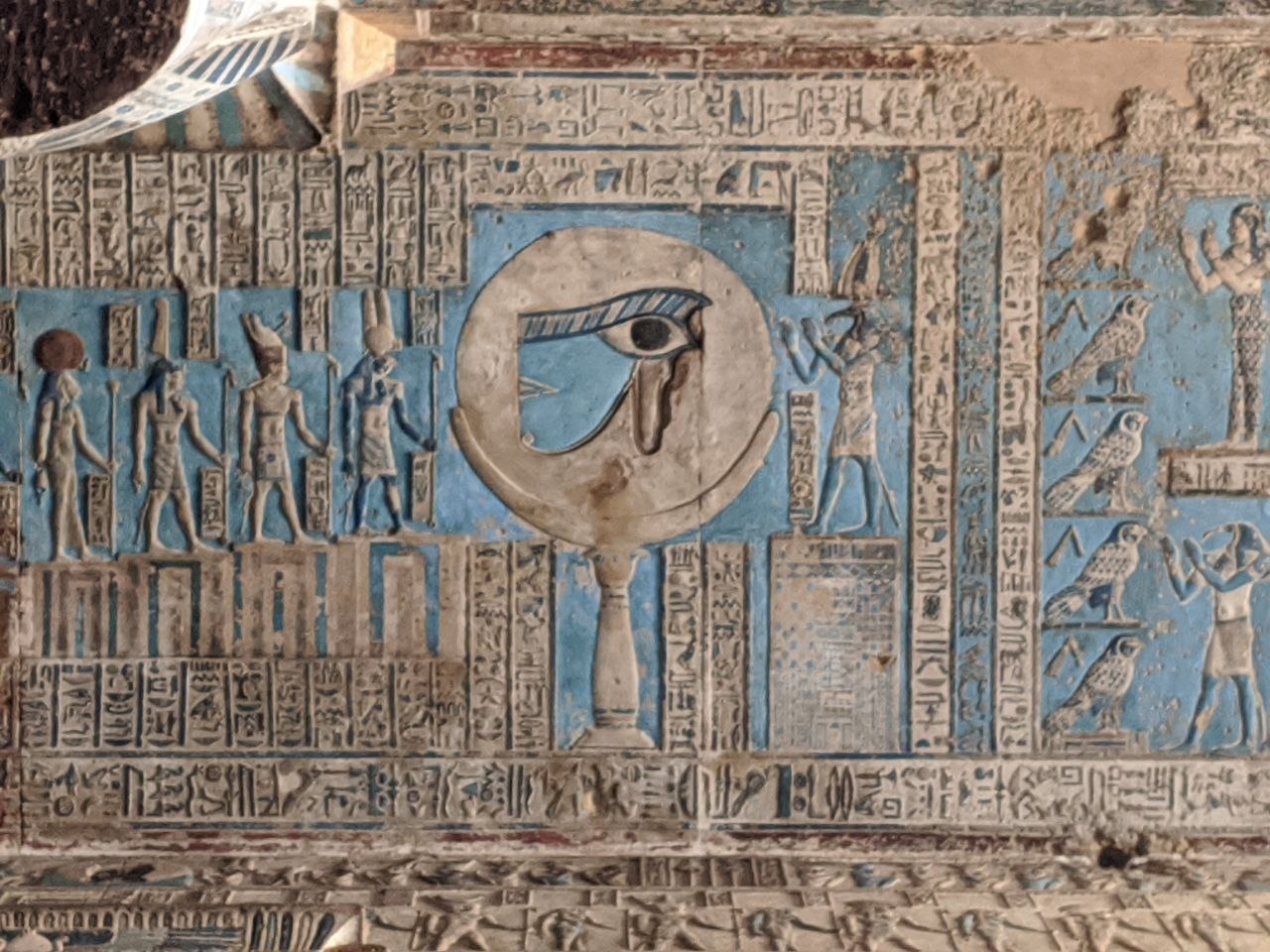 Dendera ceiling panel featuring the Eye of Horus in a circular cartouche surrounded by deities on blue background