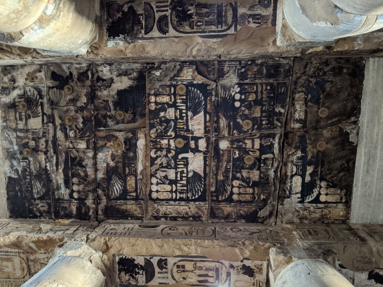 Soot-blackened ceiling of Abydos temple with damaged painted astronomical and religious scenes still visible between columns