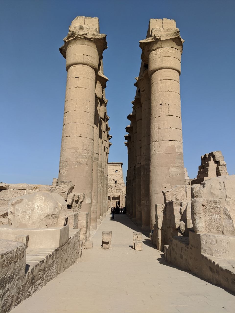 Two massive papyrus columns of the Great Hypostyle Hall framing a gateway leading deeper into the Karnak complex