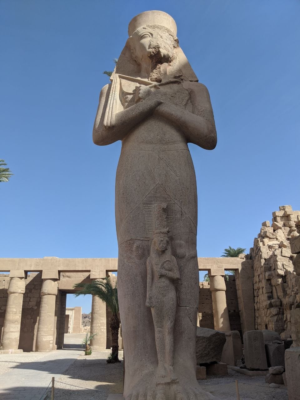 Standing colossal statue of Ramesses II in mummiform with a smaller figure of Queen Nefertari carved between his legs, Karnak Temple