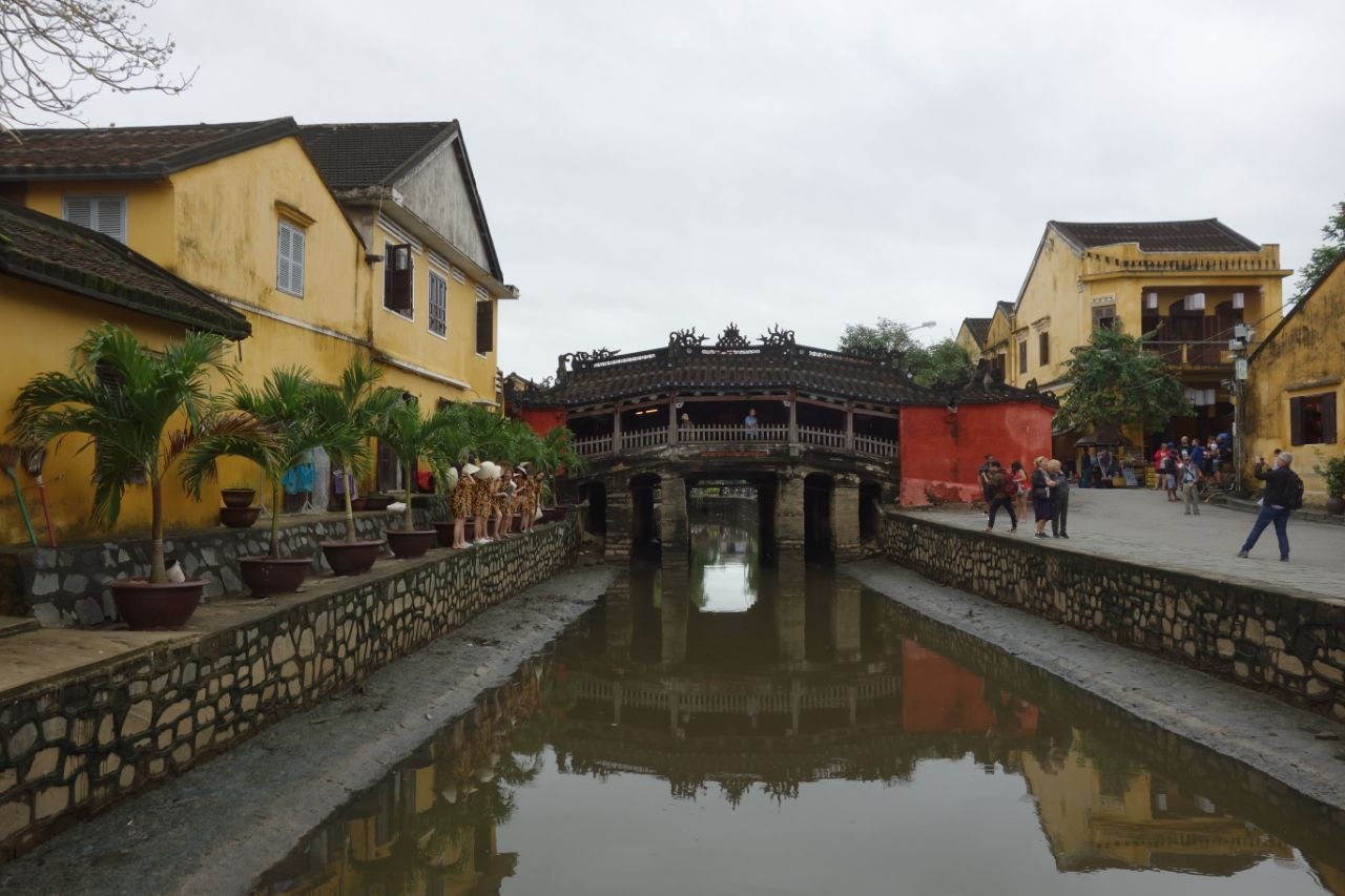 The Japanese Covered Bridge (Chùa Cầu) in Hoi An, painted deep ochre-red with a pagoda shrine on its northern side