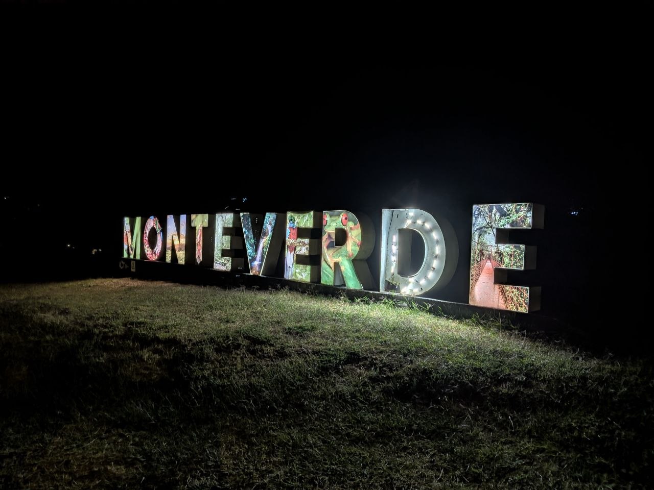 The illuminated Monteverde sign at night, decorated with wildlife and nature imagery, Santa Elena, Costa Rica